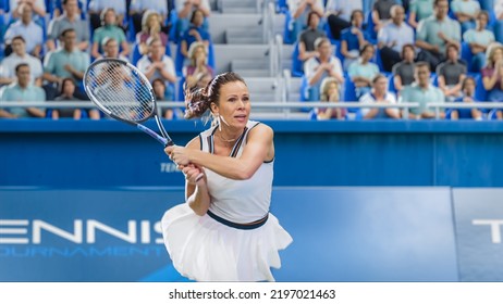 Female Tennis Player Hitting Ball With A Racquet During Championship Match. Professional Woman Athlete Recieving Ball. World Sports Tournament With Audience Cheering. Crowd Supporting Sportswoman.