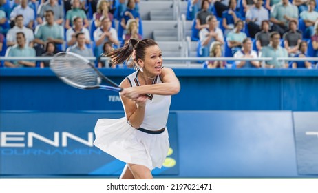 Female Tennis Player Hitting Ball With A Racquet During Championship Match. Professional Woman Athlete Striking Ball. World Sports Tournament With Audience Cheering. Crowd Supporting Sportswoman.