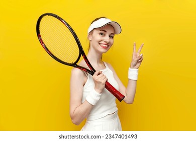 female tennis player in sportswear holding tennis racket and showing peace gesture on yellow isolated background, female tennis coach in white uniform greets - Powered by Shutterstock