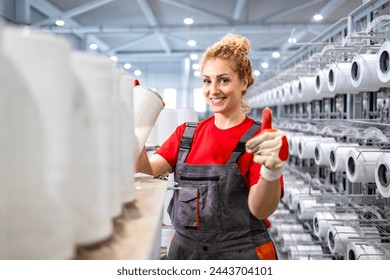 Female textile factory worker with thread spools holding thumbs up. - Powered by Shutterstock