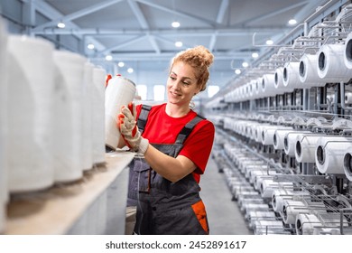 Female textile factory worker with thread spools and industrial sewing machine in background. - Powered by Shutterstock