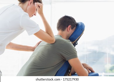 Female therapist giving back massage to man in hospital