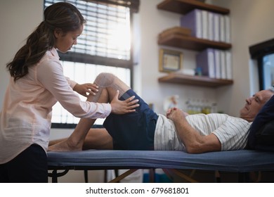 Female therapist measuring knee while senior male patient lying on bed at hospital ward - Powered by Shutterstock