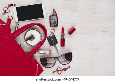 Female things and red handbag on wooden background with copyspace
