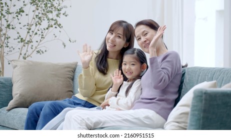 Female Three Generation Family Waving To The Camera In The Living Room