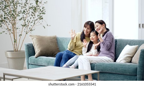 Female Three Generation Family Waving To The Camera In The Living Room