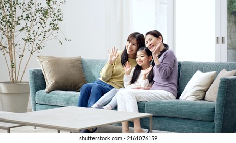 Female Three Generation Family Waving To The Camera In The Living Room