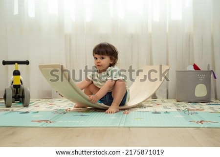 Female toddler wobbling on a balance board in her playroom. 