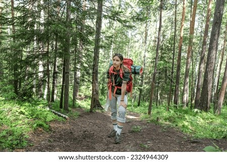 Female tourist with backpack and mat stoped to have a rest in walking in forest