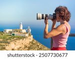 Female tourist with camera taking travel photo from Mesa Roldan lighthouse, Cabo de Gata Nijar Natural Park in Almeria province, Andalusia Spain.