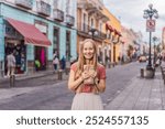 Female tourist eating churros on a colonial street in Puebla, Mexico. Cultural experience, local cuisine, and street food exploration concept