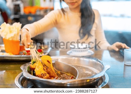 Female tourist eating original mala spicy hot pot (Chuan Chuan) at restaurant in Chengdu, China