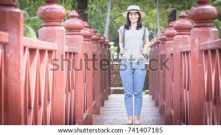 Female tourist with happy gesture on red wooden bridge.At Sukhothai Historical Park,Thailand.