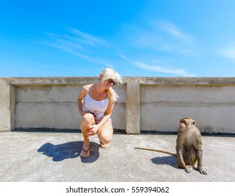 Female Tourist Looking At Monkey And Smiling At Daytime With Blue Sky, Summer Time, Travel Concept And Copy Space