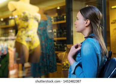 Female tourist looking at the shop window of clothing store.