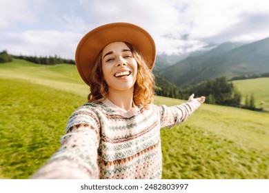 Female tourist is making a selfie in the middle of hills surrounded by green nature. Technology, travel, blogging concept. - Powered by Shutterstock