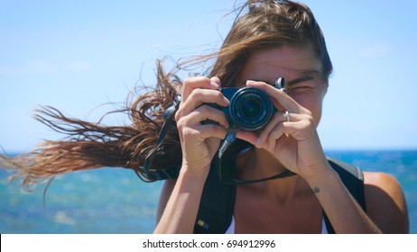 A Female Tourist Photographer Is Taking Pictures, With A Backpack On Her Back, A Wonderfully Beautiful View Of The Blue Sea And Sky. Concept: Travel, Vacation, Photo Camera, Photo Courses, Lifestyle.