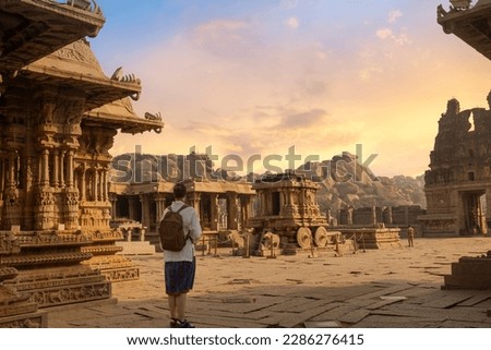 Female tourist sightseeing at Vijaya Vittala temple with medieval architecture at sunset at Hampi, Karnataka India