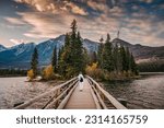 Female tourist standing on wooden bridge and tiny island on Pyramid Lake in the evening at Jasper national park, AB, Canada