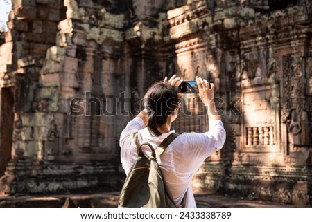Female tourist taking photo of ancient Angkor temple in Cambodia