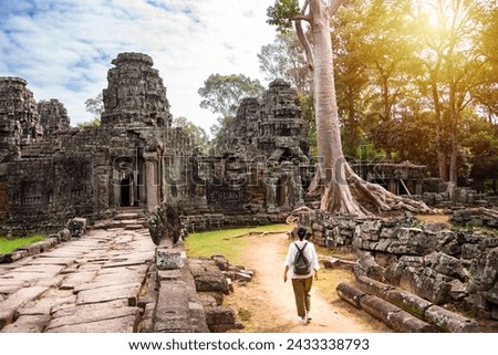 Female tourist walking to ancient Angkor temple in Cambodia