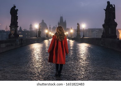 Female tourist walking on the Charles Bridge alone during a foggy morning in Prague, capital of Czech Republic