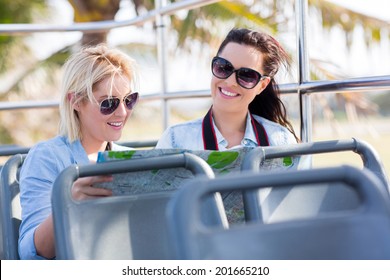 female tourists traveling on a open top bus and looking at a map