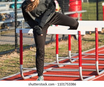 A Female Traack And Field Runner Is Warming Up For Her Hurdles Race By Performing Hurdle Walk Overs At A Track Meet.