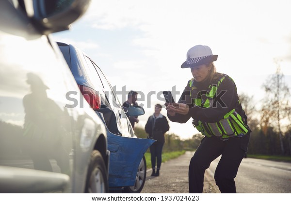 Female Traffic Police Officer Taking\
Photos On Mobile Phone At Road Traffic\
Accident