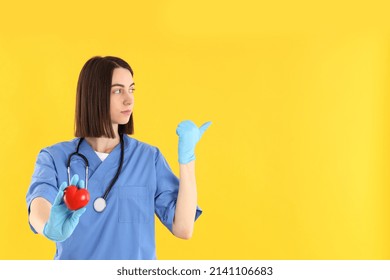 Female Trainee Nurse With Heart On Yellow Background