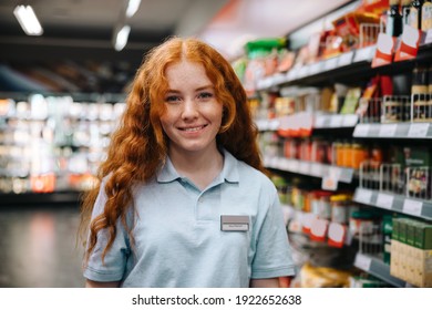 Female trainee in a supermarket. Woman working in a grocery store smiling at camera.