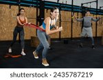 Female trainer helping girl to train with resistance band in gym