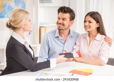 Female Travel Agent Giving Tickets To Young Happy Couple.