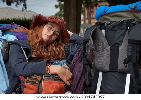 Female traveler in colorful clothes sleeping at a train station bench, young woman traveling the wolrd