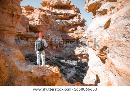 Female traveler enjoying beautiful landscapes standing between the huge rocks volcanic origin on a sunny day. Traveling on Tenerife island, Spain