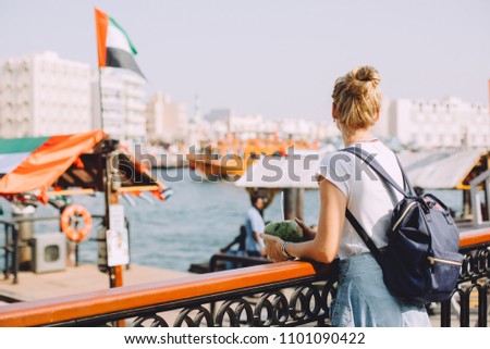 Female traveler looking at modern city architecture against blue sky, Dubai, old town