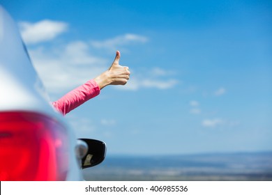 Female traveler on the road holding thumbs up. 