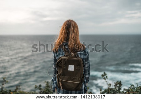 Female traveler shot from back looking at the ocean during sunset on Bali