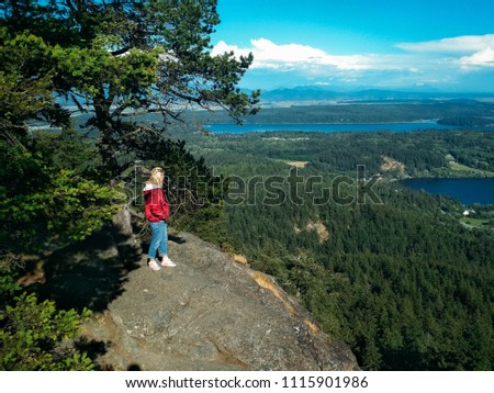 female traveler stands on a mountain in front of a landscape of lakes and forests. Olympic National Park, Washington, USA.