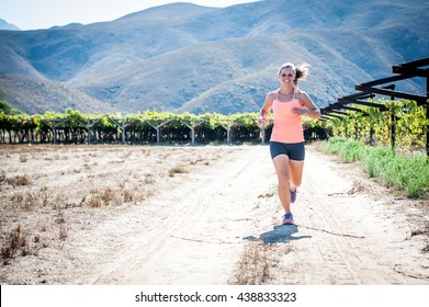 Female Triathlete Running On A Trail On A Bright Sunny Day In The Vineyards Of The Western Cape Of South Africa