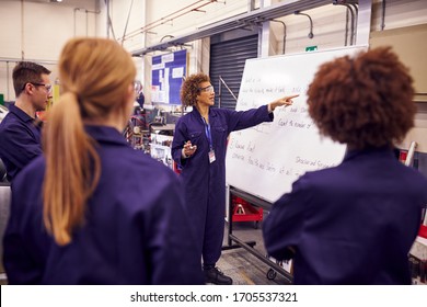 Female Tutor By Whiteboard With Students Teaching Auto Mechanic Apprenticeship At College