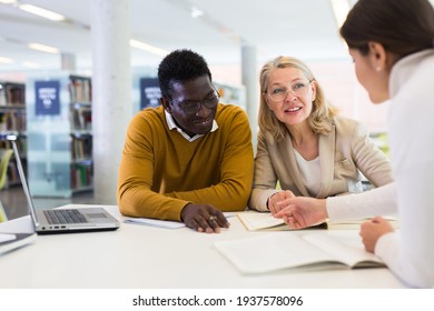 Female Tutor Helping Students Preparing For Exam In Library. High Quality Photo