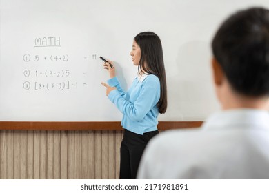 Female Tutor Standing In Front Of Whiteboard And Writing Math Equations On Board To Explaining For Student During Math Class In The Classroom