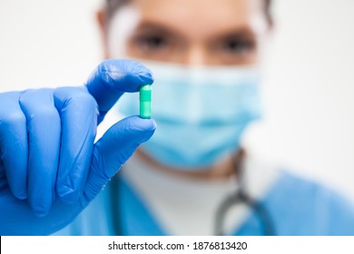 Female UK GP General Practitioner Doctor Wearing Protective Face Mask,blue Gloves,holding Green Pill,selective Detail Focus,patient Cure And Remedy For Illness Or Disease,prescription Drug Concept