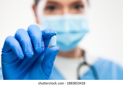 Female UK GP General Practitioner Doctor Wearing Protective Face Mask,gloves,holding Blue Pill,selective Macro Detail Focus,patient Cure And Remedy For Illness Or Disease,prescription Drug Concept