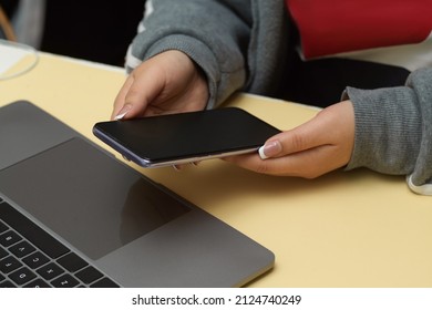 Female University Student Sitting At Her Desk And Using Her Smartphone. Close-up, Phone Black Screen