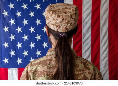 Female US Army Soldier Standing In Front Of An American Flag. Woman In Military Uniform Rear View