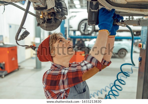 Female using\
an impact wrench at a service\
station