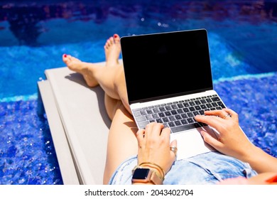 Female Using Laptop Computer On Vacation By The Pool