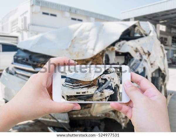 Female using mobile smart phone\
taking photo of the car crash accident damage for\
insurance